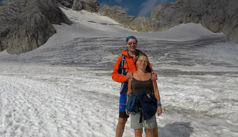 Sirpa Podrouzek ja miehensä Thomas talvella. Seisovat vähissä vaatteissa lumen keskellä.