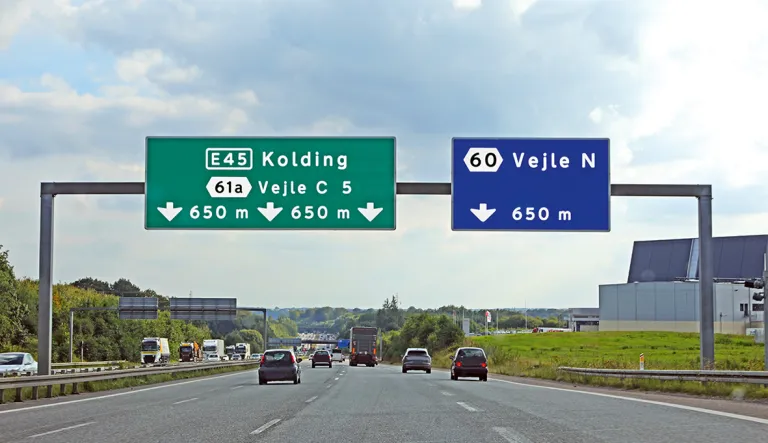 Kolding ja Vejlen välinen monikaistainen tie. Tien yläpuolella kyltit Konding ja Vejle.