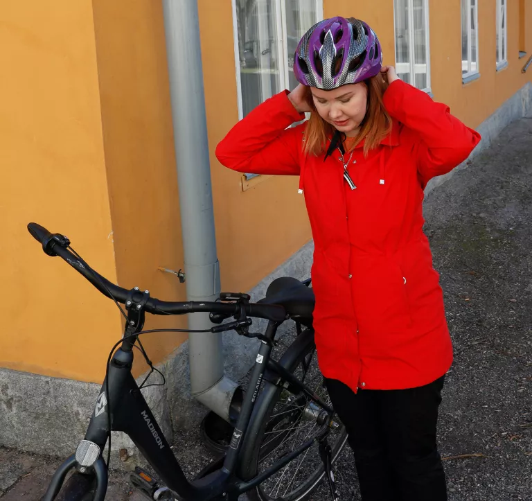 Nainen laittaa polkypyöräkypärää päähänsä.