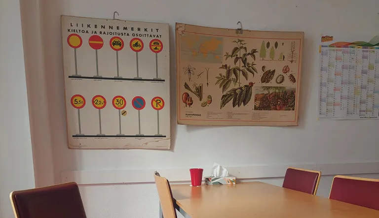 Anne Meriläisen työpiste kotona. Seinällä vanhoja pahvisia opetustauluja.