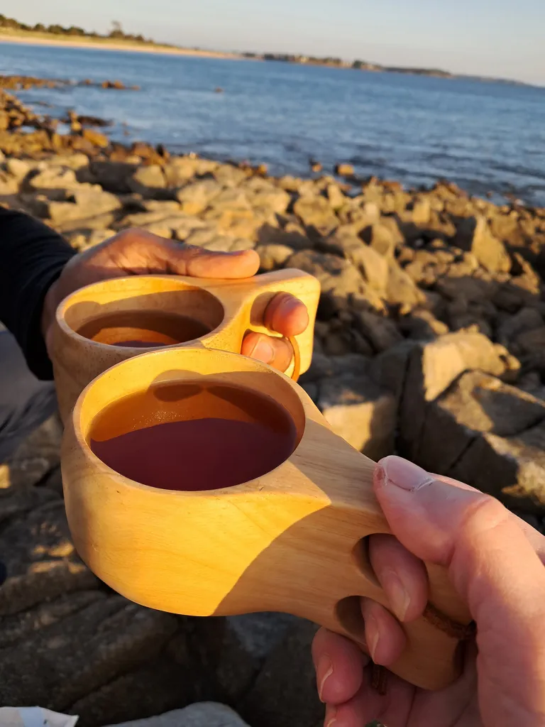 Kahvikuppeja etualalla, meri taka-alalla.