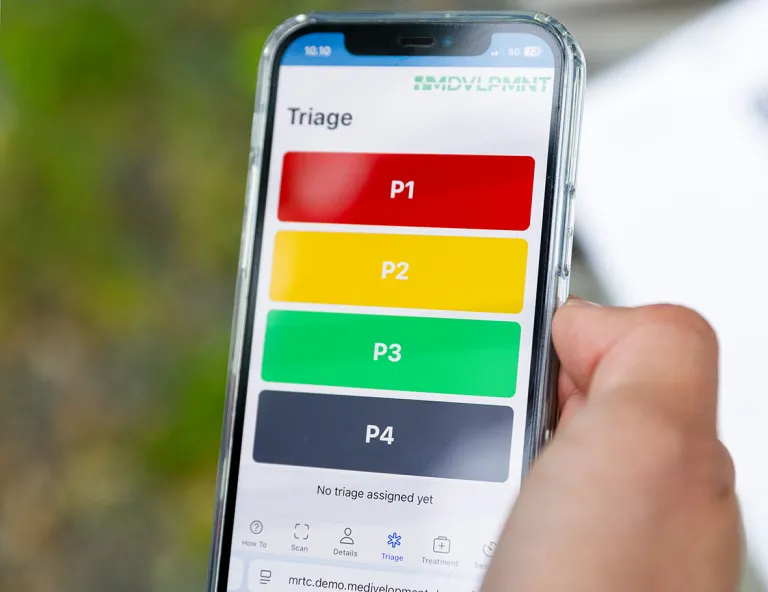 Mobiilisovelluksella harjoitellaan uhrien luokittelua. Kännykkä kädessä.