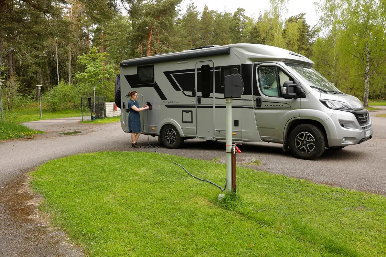 Matkailuauto pysäköitynä vihreän nurmialueen viereen.