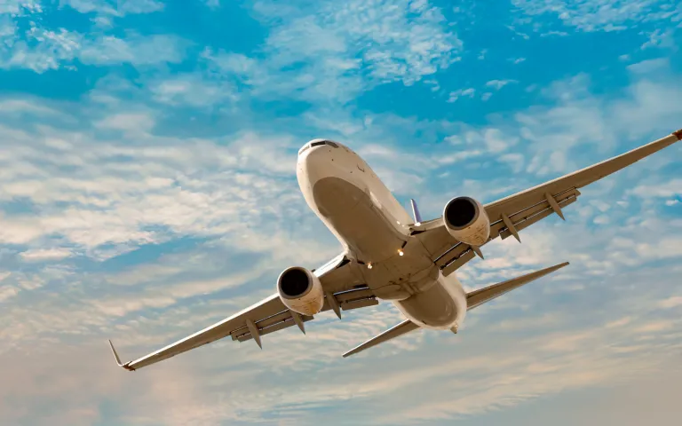 Lentokone lentää sinisellä pilvisellä taivaalla.