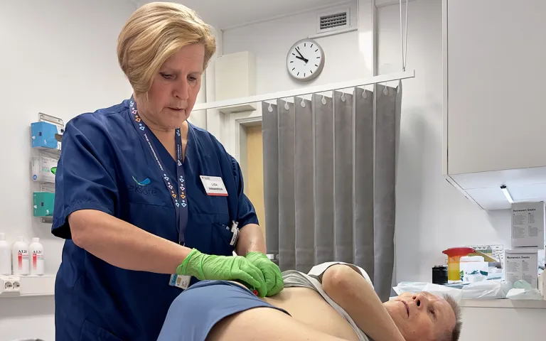 Sairaanhoitaja vaihtamassa potilaan pyelostomiakatetrin sidosta.