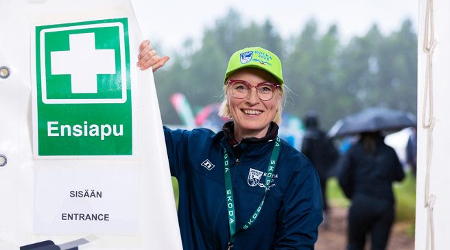 Riikka Turunen seisoo ensiapupisteen vieressä. Päässä vaalean vihreä lippalakki.