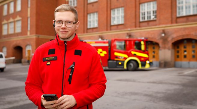 Ensihoitaja Aku-Valter Rajala seisoo ulkona paloauton edustalla.