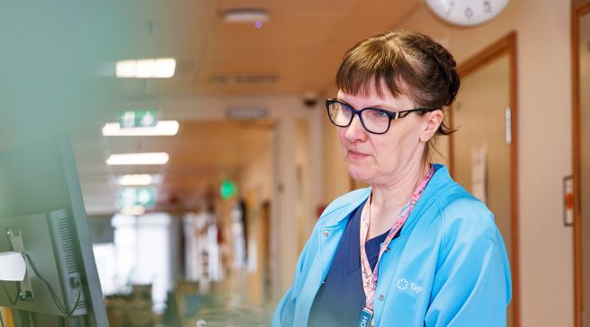 Maria Liecks tietokoneen äärellä sairaalan käytävällä.