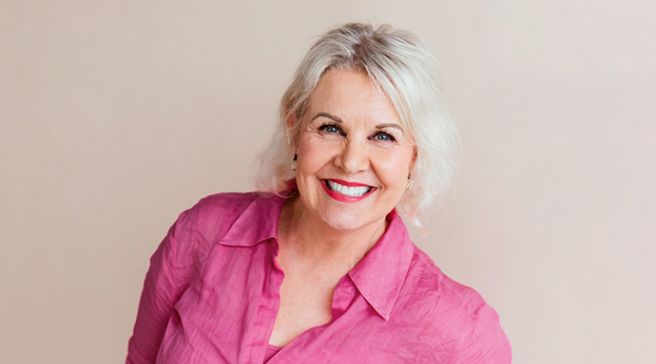 Heli Kannisto pinkissä puserossa, hymyilee.