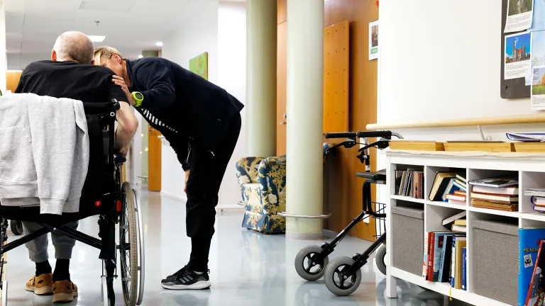 Hoitokoti Wilhelmiinan käytävältä kuva, jossa vanhus ja hoitaja.