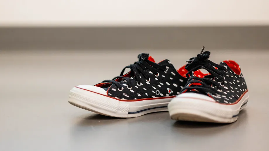 Musta-puna-valkoiset tennarit lattialla vierekkäin.