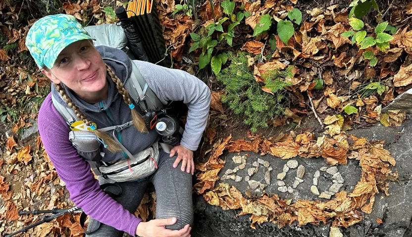 Sairaanhoitaja Anu Rajala vaelluksellaan metsässä kirjoitti kivillä ja lehdillä asetellen vuosiluvun 2000 kiven päälle.