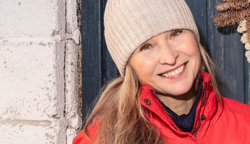 Sairaanhoitaja Merja Ahosen kasvokuva. Päässä pipo ja päällä punainen talvitakki.