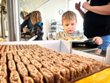 Lapsi ottaa itse oman lounaansa päiväkodin linjastolta tarjottimensa kanssa. Linjaston päädyssä näkyy näkkileipiä.