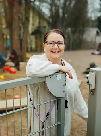 Lastenhoitaja Jonna Vilenius hymyilee päiväkodin portilla.
