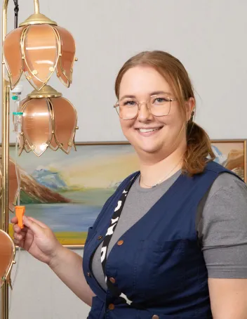 Laura Haapatalo tippatelineen vieressä. Tippatelineenä toimii jalkalamppu..