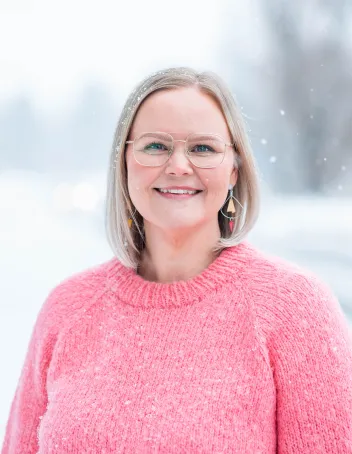 Kasvokuva Veera Siidoroffista lumisateessa. Päällä pinkki villapaita.